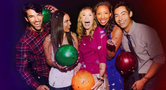 5 bowlers holding up bowling balls and smiling