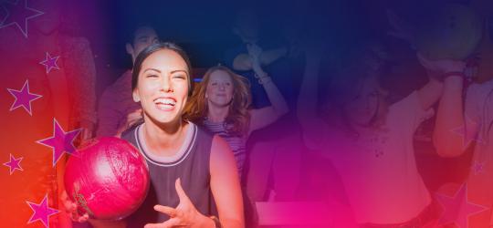 woman holding bowling ball with crowd cheering behind her