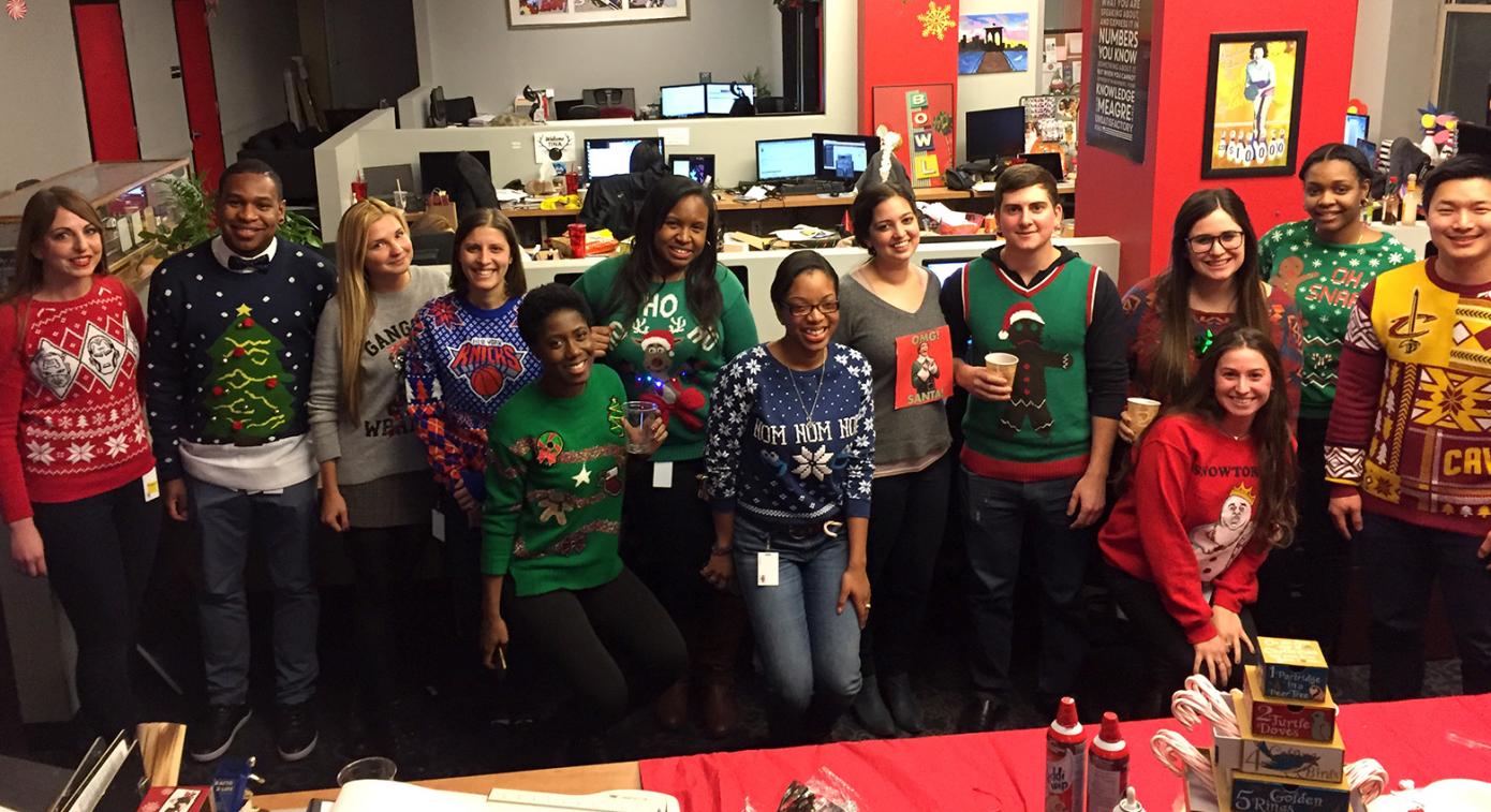 Employees wearing ugly sweaters by desks